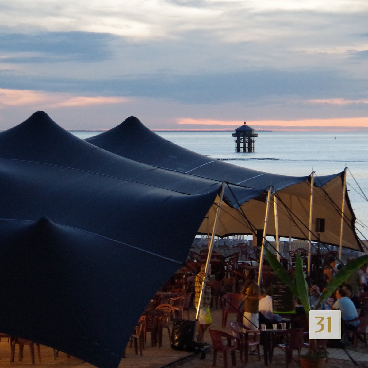 Black BT stretch tents as a beach terrace at sunset by the sea